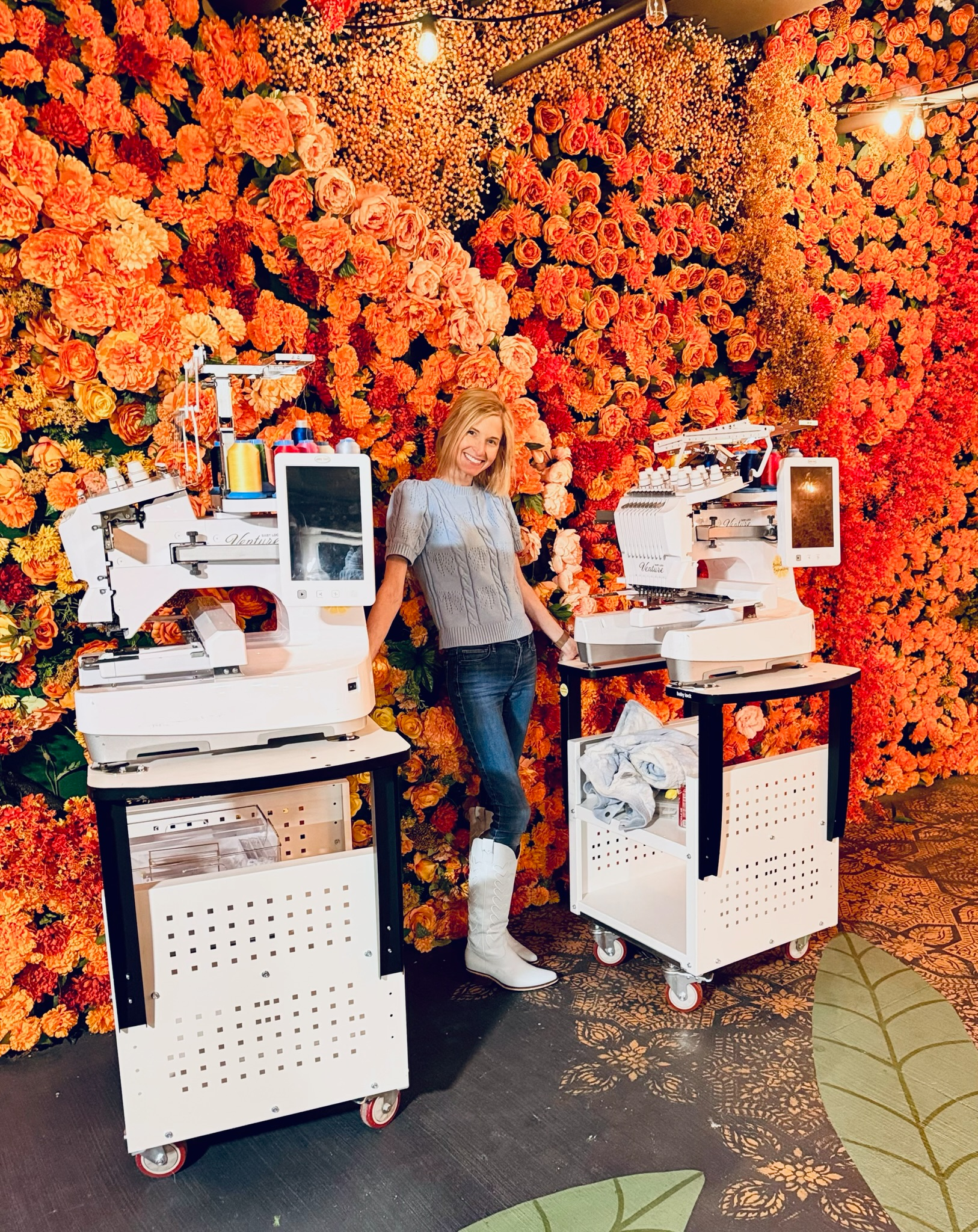 Emily stitching on-site in front of an orange floral wall